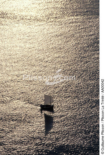 Un petit canot à misaine dans une mer d'huile au soleil couchant, - © Guillaume Plisson / Plisson La Trinité / AA00042 - Nos reportages photos - Vieux gréement